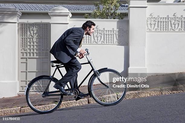 businessman struggling to cycle up steep hill - 上り坂 ストックフォトと画像