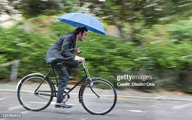 businessman cycling in the rain with umbrella - man with umbrella stockfoto's en -beelden