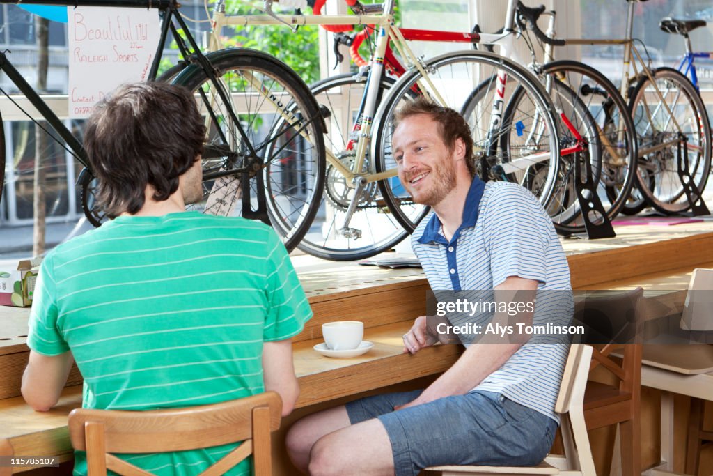 Two young men in cafe with bikes