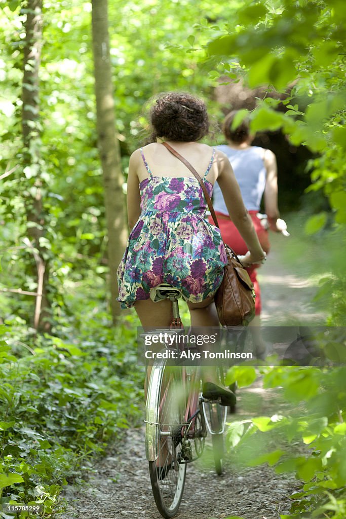 Back of girl riding bike through forest