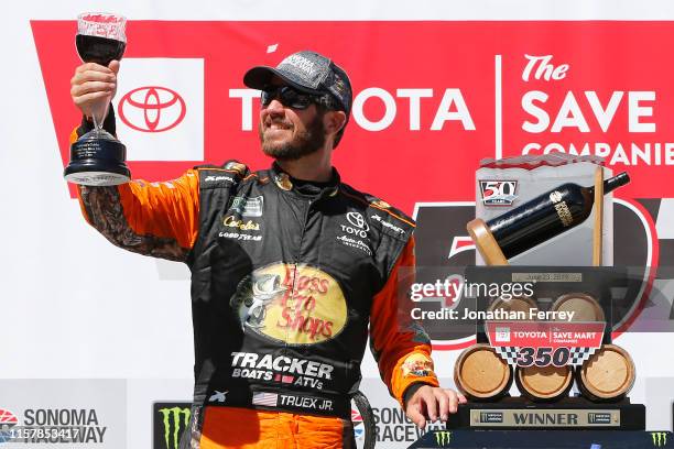 Martin Truex Jr., driver of the Bass Pro Shops Toyota, poses with the trophy in Victory Lane after winning the Monster Energy NASCAR Cup Series...