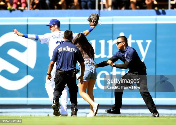 Cody Bellinger of the Los Angeles Dodgers reacts as a fan chases after him on the field during the ninth inning against the Colorado Rockies at...