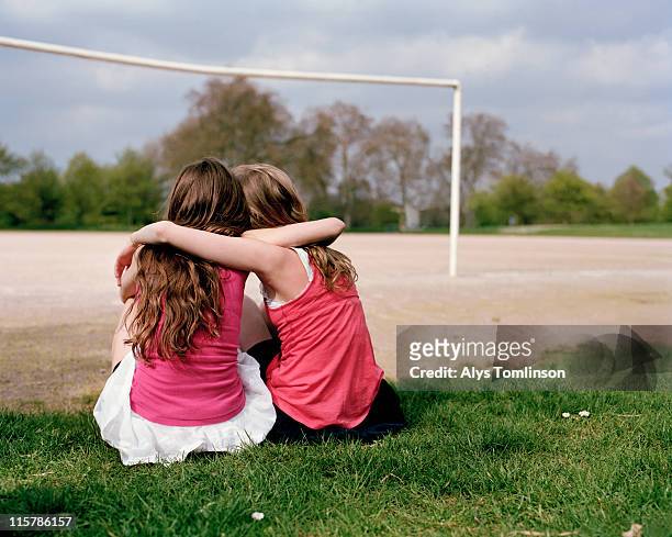 two girls on a playing field hugging - girl friends foto e immagini stock