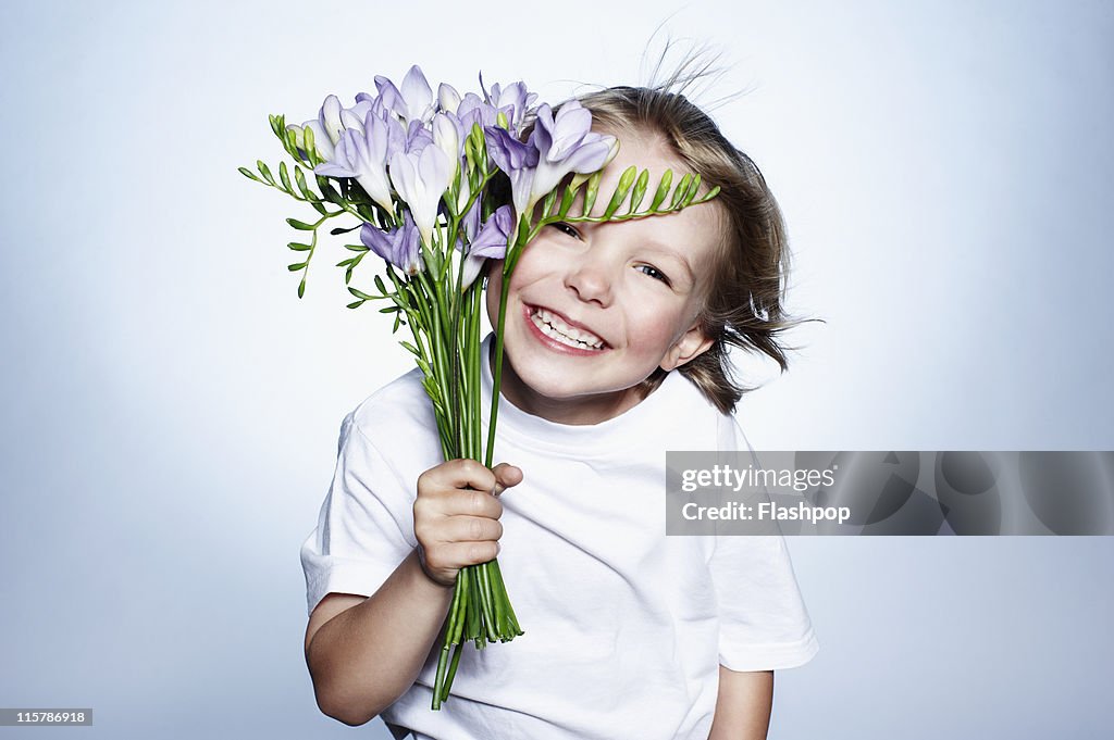 Boy smiling holding bunch of flowers