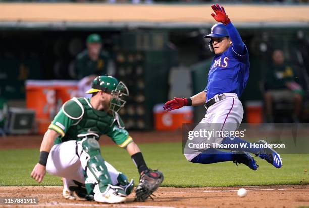 Shin-Soo Choo of the Texas Rangers scores as catcher Chris Herrmann of the Oakland Athletics can't hold on to the ball in the top of the fourth...