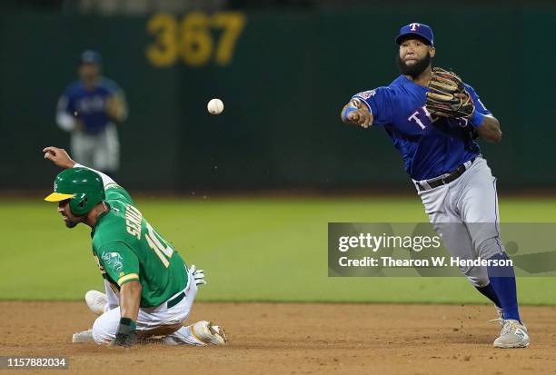 Danny Santana of the Texas Rangers completes the double-play throwing over the top of Marcus Semien of the Oakland Athletics in the bottom of the...
