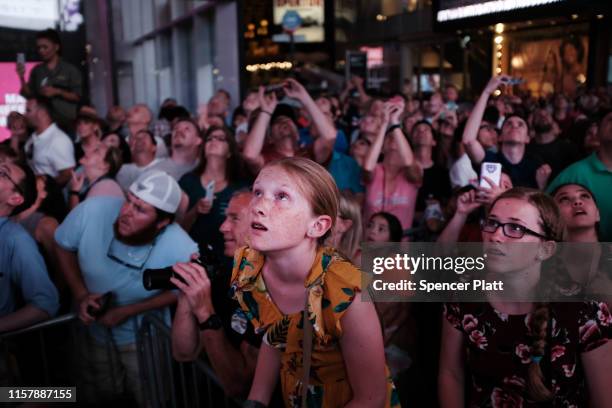 People watch as Nik Wallenda and Lijana Wallenda cross Times Square on a high wire strung between two skyscrapers 25 stories above the pavement on...