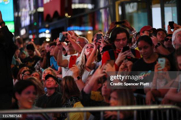 People watch as Nik Wallenda and Lijana Wallenda cross Times Square on a high wire strung between two skyscrapers 25 stories above the pavement on...