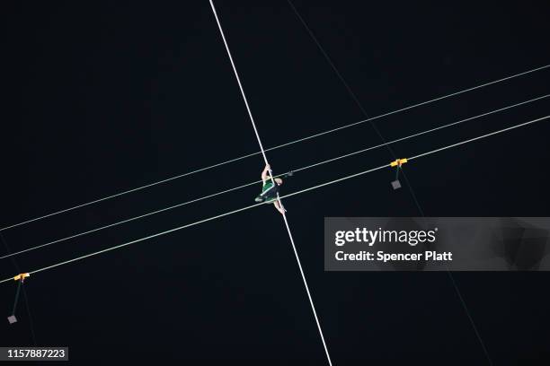 People watch as Nik Wallenda and Lijana Wallenda cross Times Square on a high wire strung between two skyscrapers 25 stories above the pavement on...