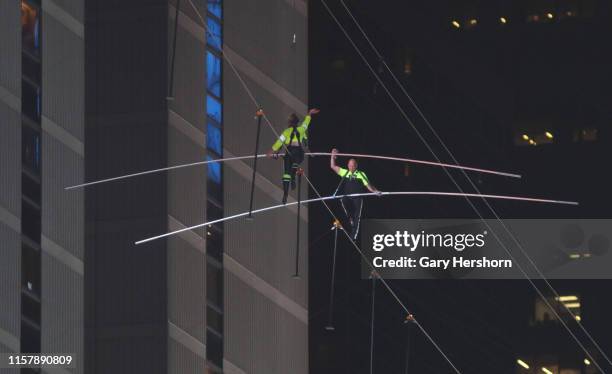 Nik Wallenda waves with his sister Lijana Wallenda as they meet in the center of their highwire walk above Times Square on June 23, 2019 in New York...