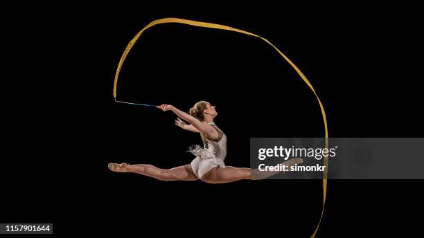 gymnast doing rhythmic gymnastics with yellow ribbon - ribbon-routine-rhythmic-gymnastics stock pictures, royalty-free photos & images