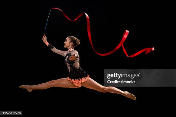 gimnasta haciendo gimnasia rítmica con cinta roja - gimnasia rítmica fotografías e imágenes de stock