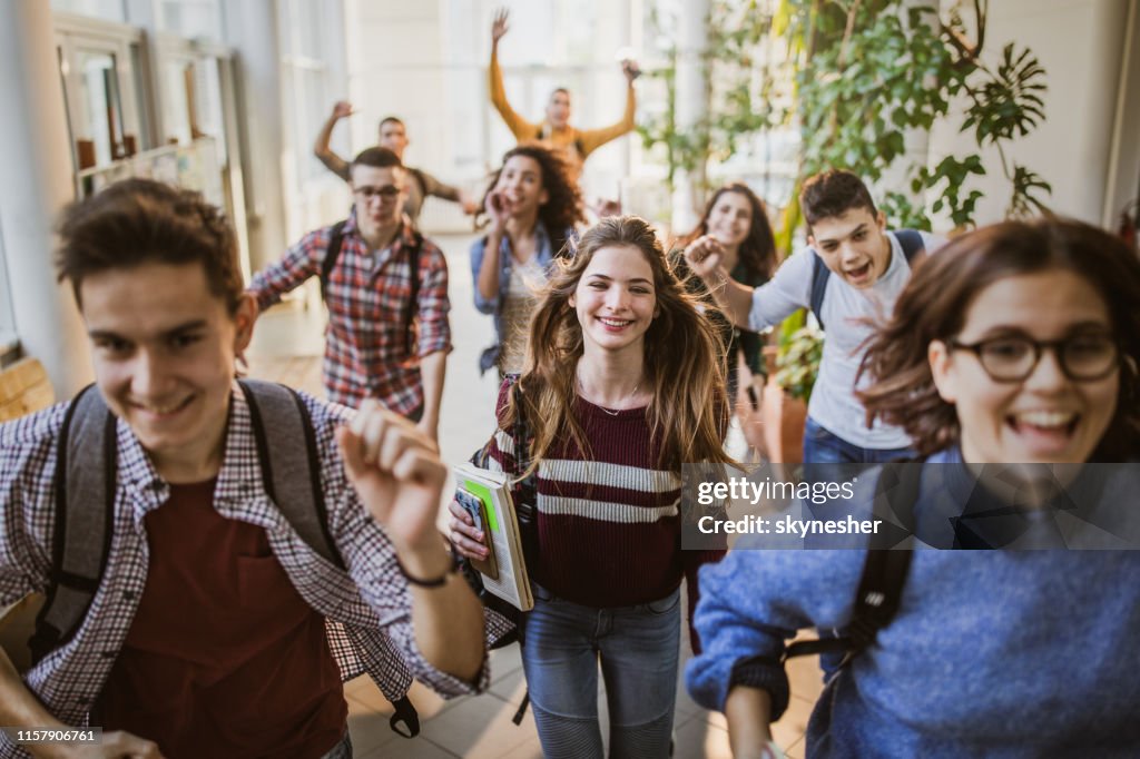 Große Gruppe fröhlicher Schüler läuft durch den Schulflur.