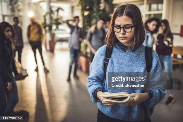 excluded high school student reading a book in a hallway. - social exclusion stock pictures, royalty-free photos & images