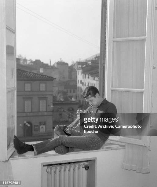 American jazz musician Chet Baker playing trumpet on a window ledge in Lucca 1961.
