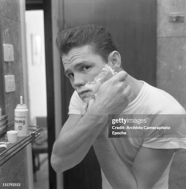 American jazz musician Chet Baker, reflected in a mirror while shaving, shaving foam on his face, Lucca 1961.