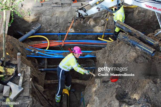 kvinna gräva ett avlopp dike på gatan. - gräva bildbanksfoton och bilder