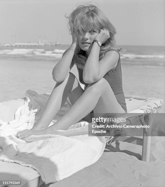 French actress Jeanne Moreau, wearing a swimming suit, sitting on a sunlounger with her elbows on the knees, at Lido beach, Venice 1961.