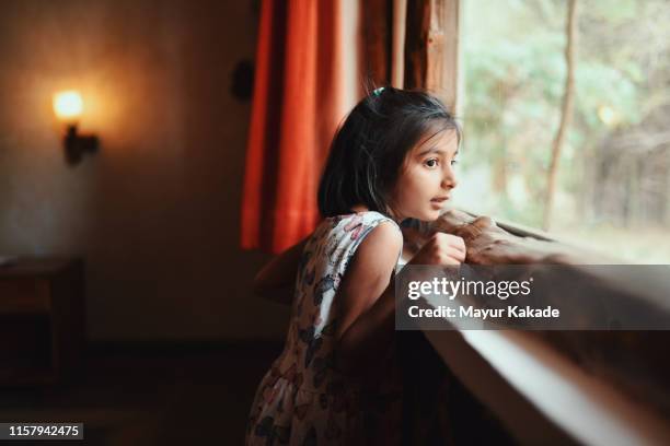 portrait of a preschool age girl looking through window - sweet indian home stock pictures, royalty-free photos & images