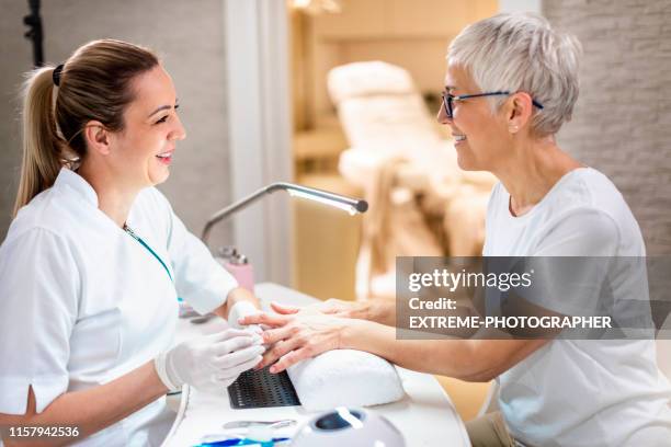 female manicurist working on a senior woman's manicure in a beauty salon - white glove cleaning stock pictures, royalty-free photos & images