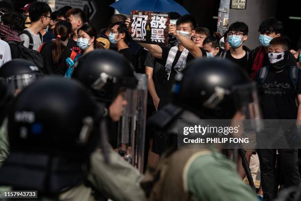 Police officers stand guard outside a village in Yuen Long district in Hong Kong as people attend a march on July 27, 2019. - Riot police fired tear...
