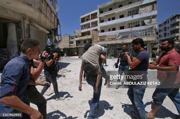 Graphic content / A Syrian man carries the body of a victim at the site of a reported air strike on the town of Ariha, in the south of Syria's Idlib...