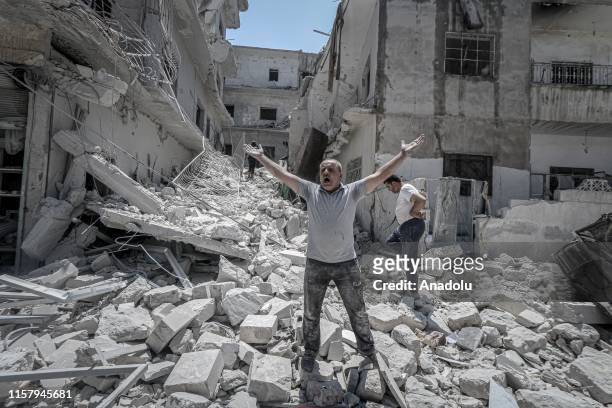 Man shouts with open hands over the debris of his damaged house after airstrikes of Assad Regime and Russia over Arihah district within the...