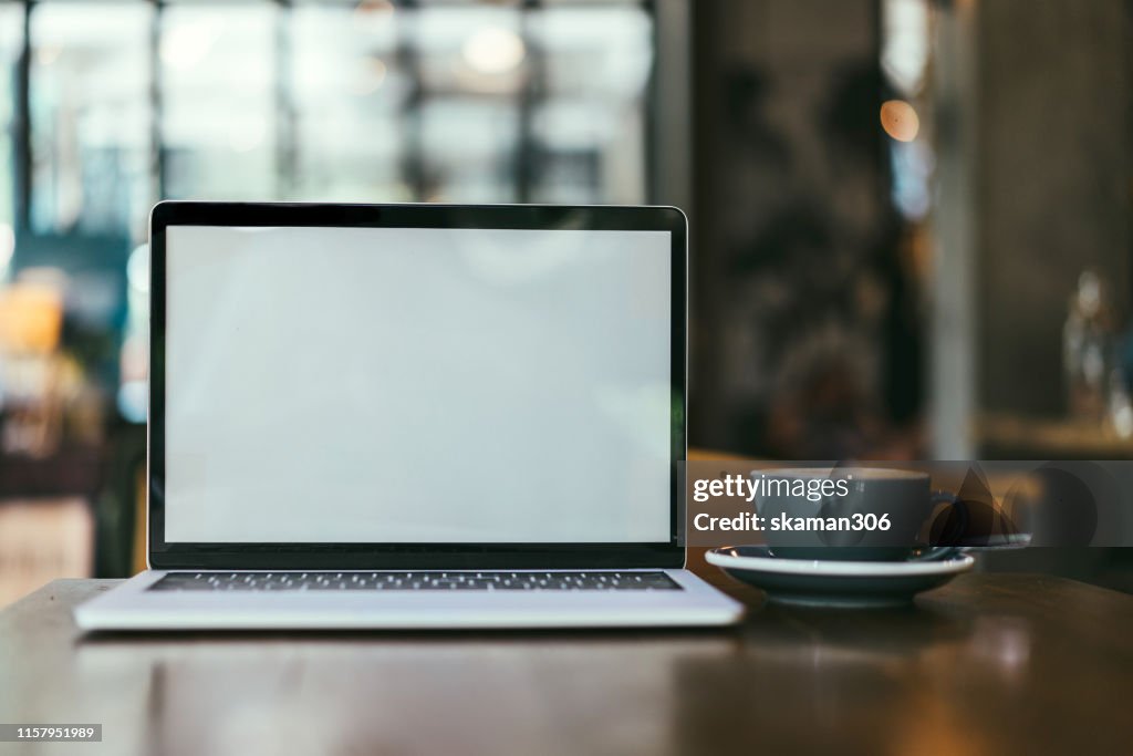 Closeup blank screen laptop computer and coffee on wooden table and copyspace