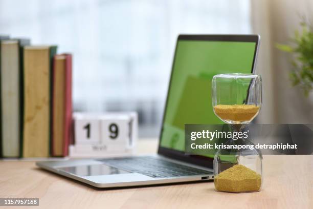 hourglass with books and notebooks as background,hourglass, reading table, desk - hourglass books fotografías e imágenes de stock