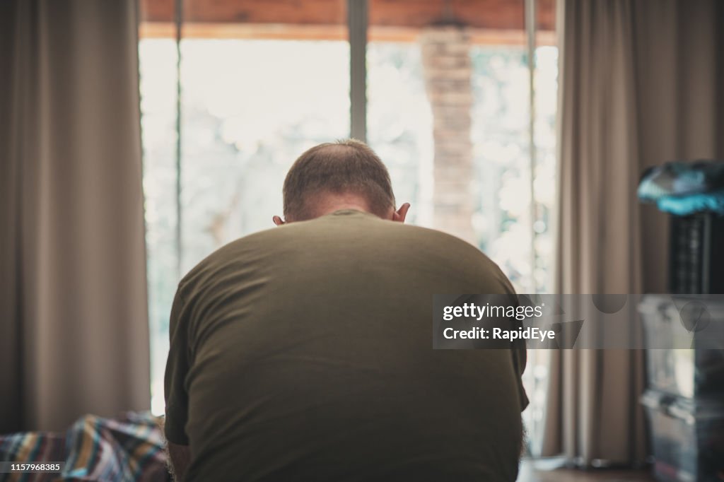 Tired and despairing mature man in his bedroom in the morning