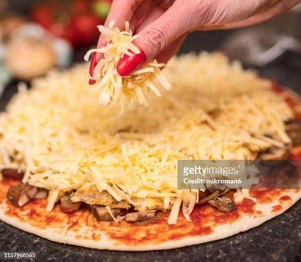 grated cheese. preparing pizza in the kitchen for dinner. - grated cheese stock pictures, royalty-free photos & images