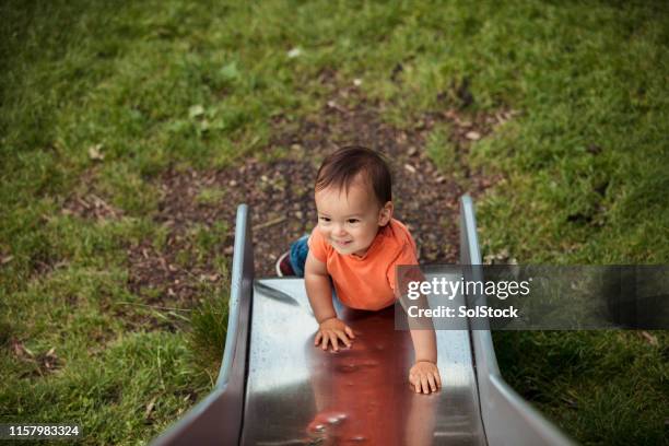 young boy playing on a slide outdoors - baby slide stock pictures, royalty-free photos & images