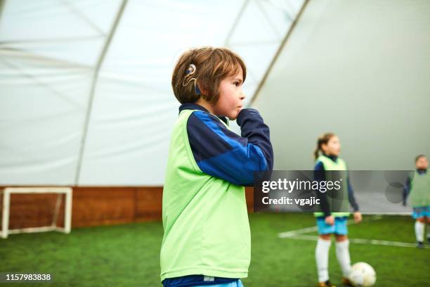 cute boy mit cochlea implantat bei kinder fußball training - implantat stock-fotos und bilder