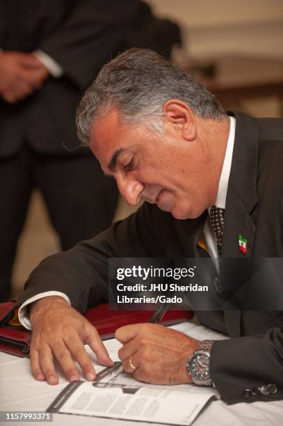 Profile close-up of Reza Pahlavi, Crown Prince of Iran, signing a program during a Milton S Eisenhower Symposium at the Johns Hopkins University,...