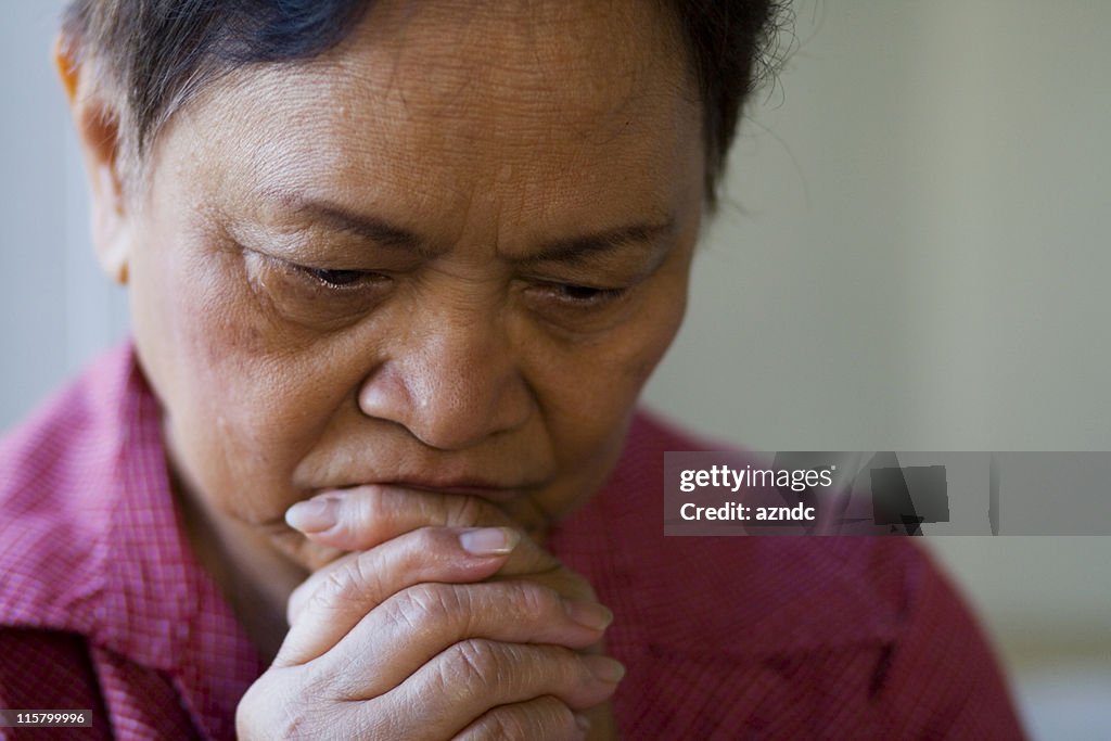 Tired woman places hands over mouth and chin deep in thought