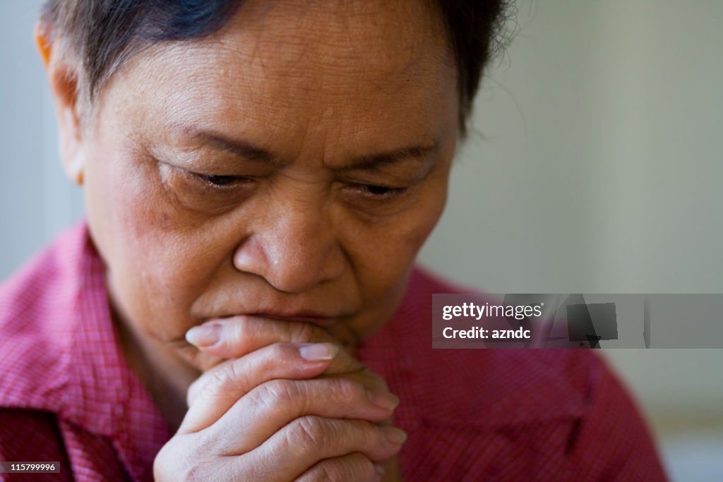 Tired woman places hands over mouth and chin deep in thought