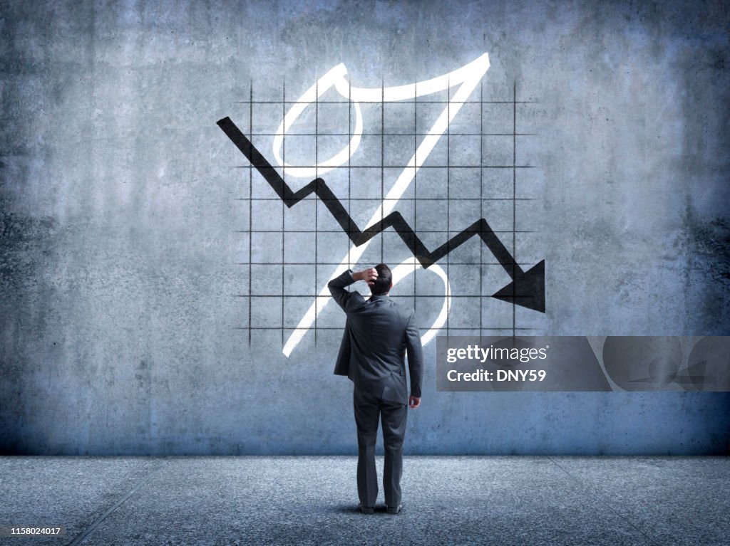 Businessman Looking Up At Falling Interest Rates