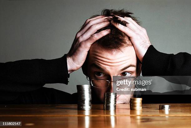 young man holding his head counting pennies - kärleken till pengar bildbanksfoton och bilder