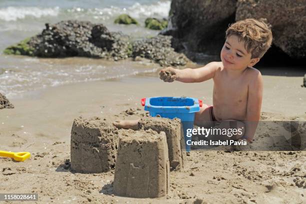 boy building sandcastles on beach - sand castle bildbanksfoton och bilder