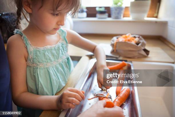 child learning to peel vegetables with adult supervision - peeler stock pictures, royalty-free photos & images