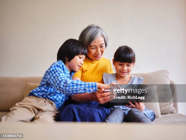 großmutter liest kindern in einem heim in taiwan - asian woman reading stock-fotos und bilder