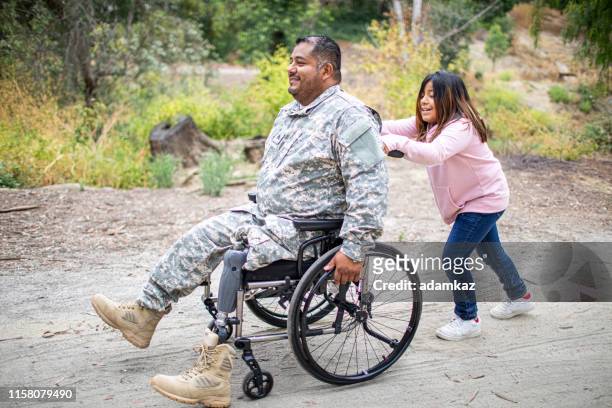little girl pushing her dad in a wheelchair - injured us army stock pictures, royalty-free photos & images