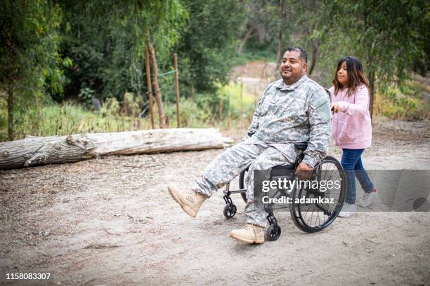 little girl pushing her dad in a wheelchair - injured us army stock pictures, royalty-free photos & images