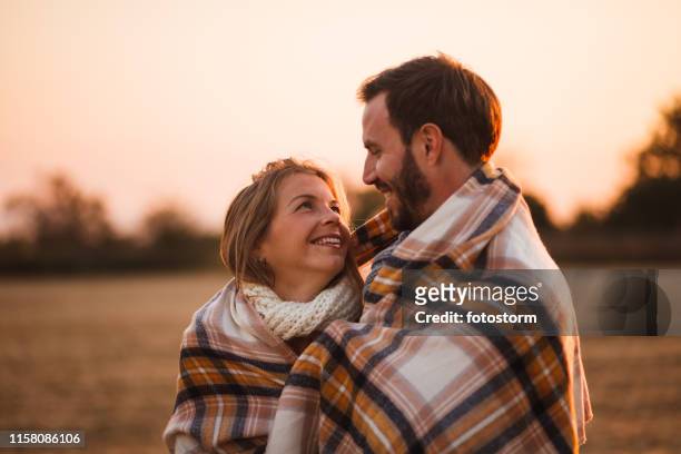 couple wrapped in a blanket outdoors - cosy autumn stock pictures, royalty-free photos & images