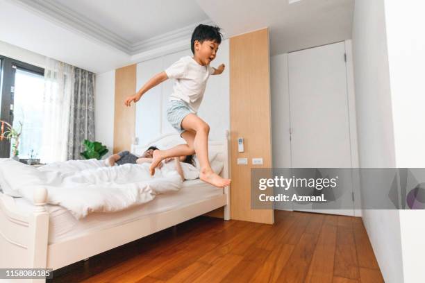 playful taiwanese boys jumping off the bed in the morning - a boy jumping on a bed stock pictures, royalty-free photos & images