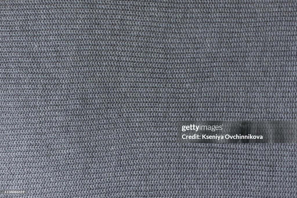 Crumpled gray knitted blanket. Soft and warm fabric crumpled in folds. Texture for background or illustrations