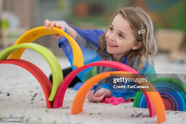 ragazza elementare carina che costruisce una struttura arcobaleno - montessori foto e immagini stock