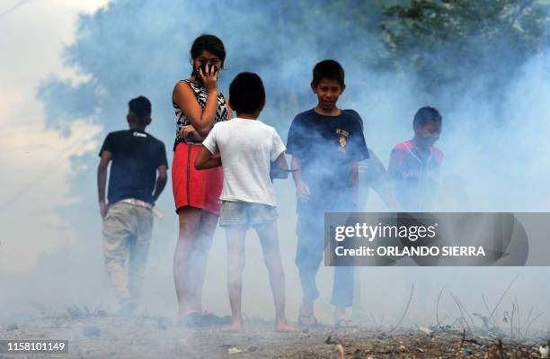 Children remain in the streets as employees of the Permanent Contingency Committee fumigate their homes during an operation to combat Aedes aegypti...