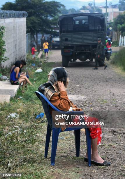 An elderly woman watches as Honduran soldiers join an operation to combat Aedes aegypti mosquitoes, vector of the dengue fever, at the Nueva Capital...