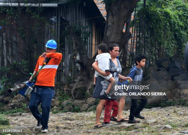 Woman and her children walk in the street as an employee of the Permanent Contingency Committee takes part in a fumigation operation to combat Aedes...